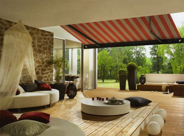 Gestreifte Markise über einer Terrasse mit Holzboden und einer Überdachung, im Hintergrund ein grüner Garten.