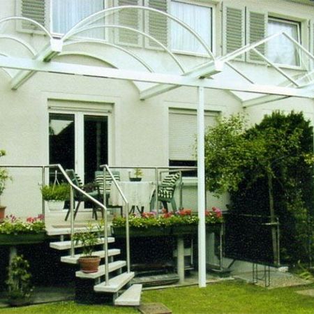 Überdachung eines Balkons im Erdgeschoss mit Blick auf einen angrenzenden Garten